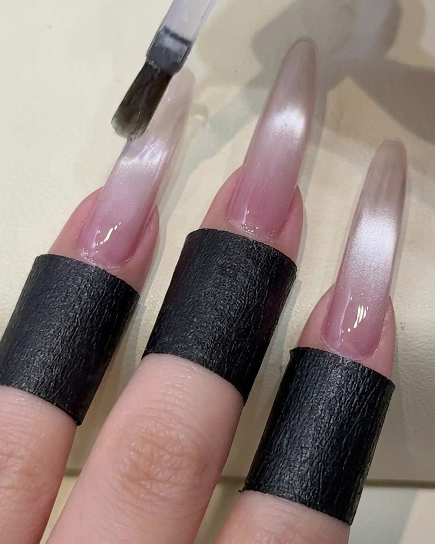 Un pennello che applica un top coat trasparente senza dispersione su ununghia con gel cat-eye.