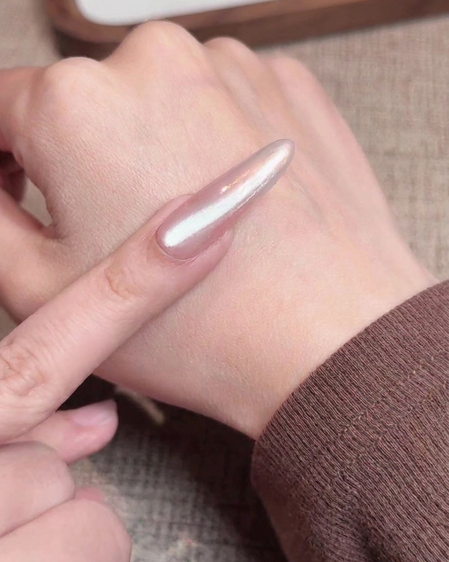 Un pennello stende uno strato di gel cat eye scintillante sopra ununghia con finitura cromo gradient.