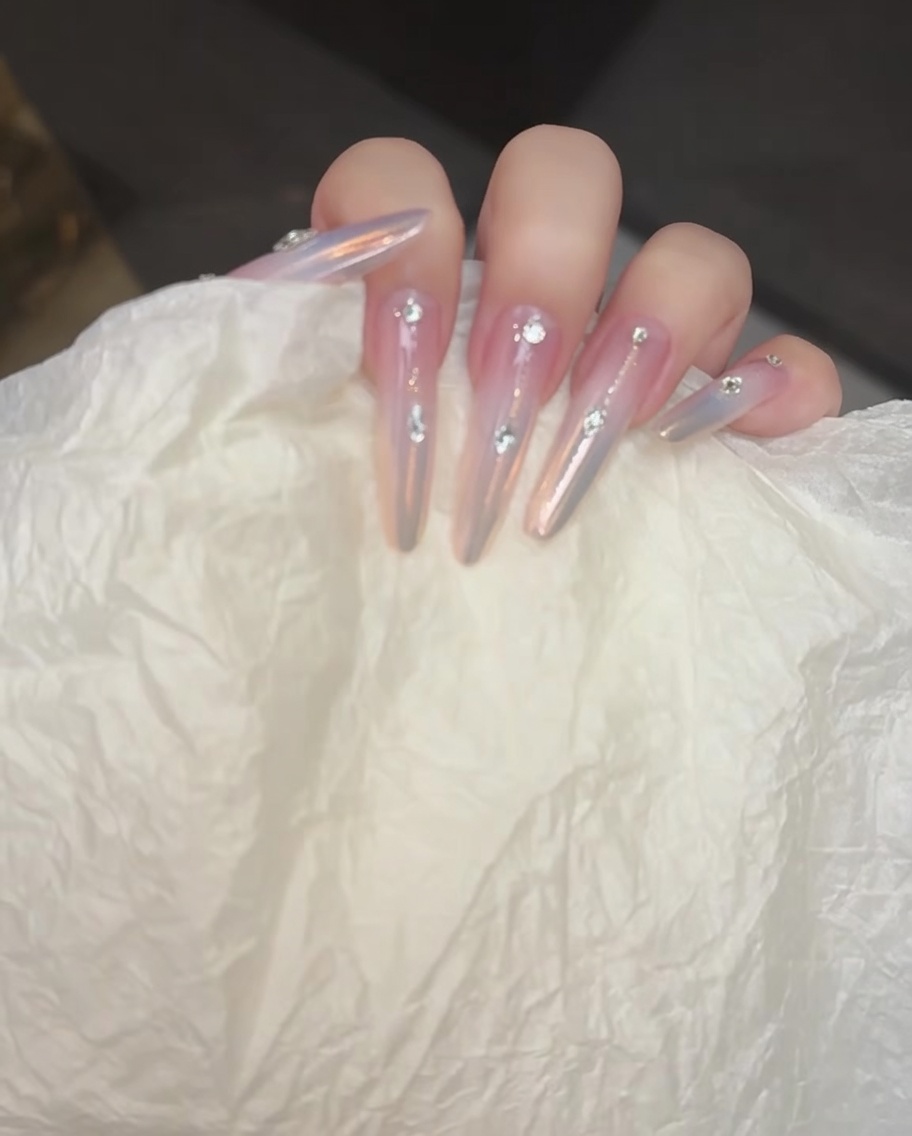 Un pennello che applica un delicato blushing gel verso il centro dellunghia.
