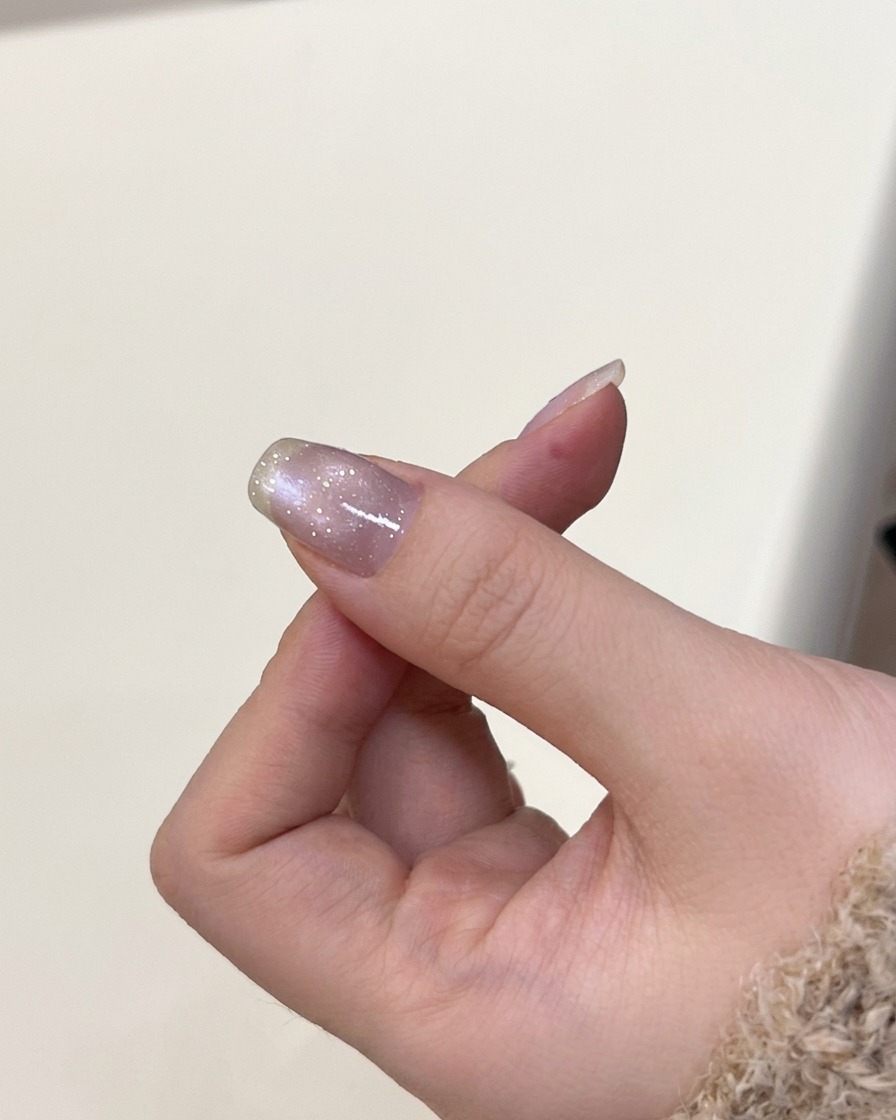 Una mano posizionata allinterno di una lampada per unghie UV per polimerizzare il gel cat-eye applicato.
