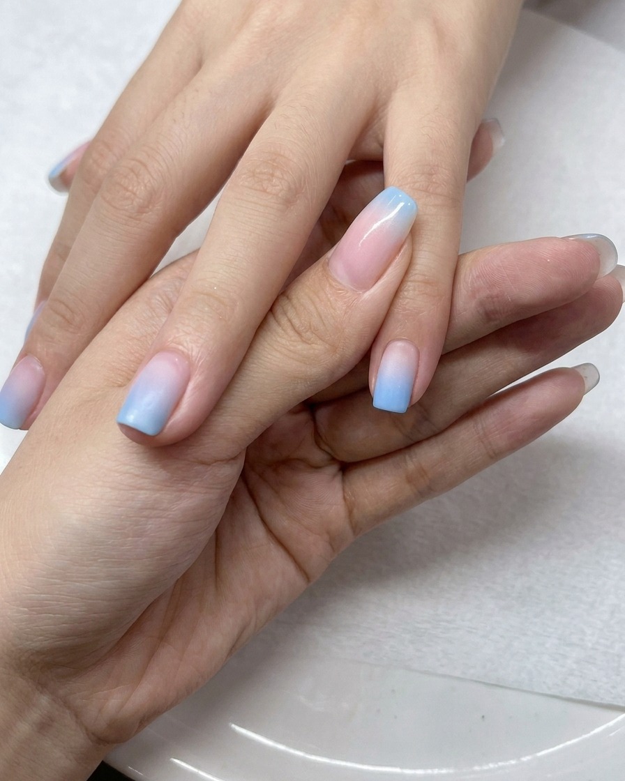 Un pennello applica uno strato di top coat gel trasparente sopra le unghie sfumate.