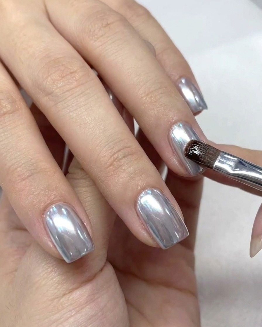 Un piccolo pennello da trucco spolvera leccesso di polvere chrome dalla cuticola e dalla pelle intorno allunghia.