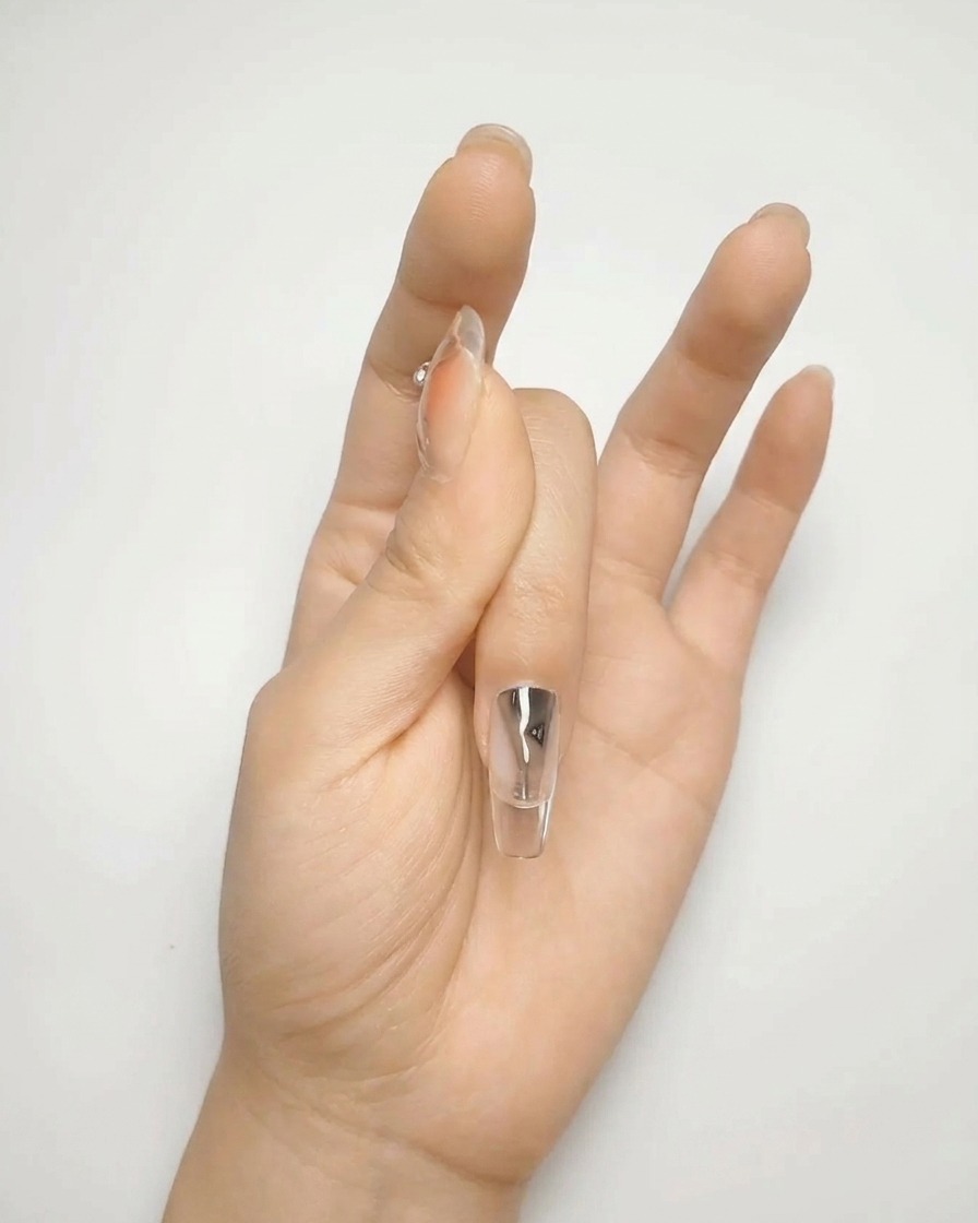 Primo piano di un pennello che applica un secondo strato di smalto gel nude, creando una superficie liscia e opaca.