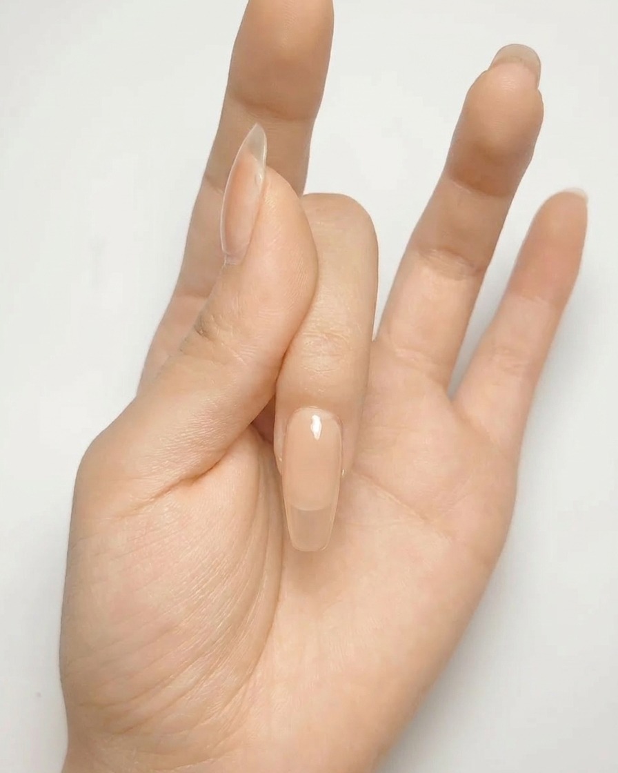 Primo piano di ununghia gel nude con una forma a croce argento dipinta sulla superficie.