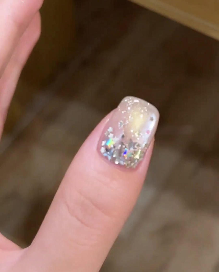 Primo piano di un pennello che applica uno strato sottile di gel bianco sulla punta di ununghia.