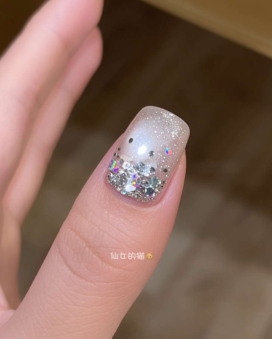 Un pennello che applica uno strato finale di top coat lucido su ununghia decorata con stelle.