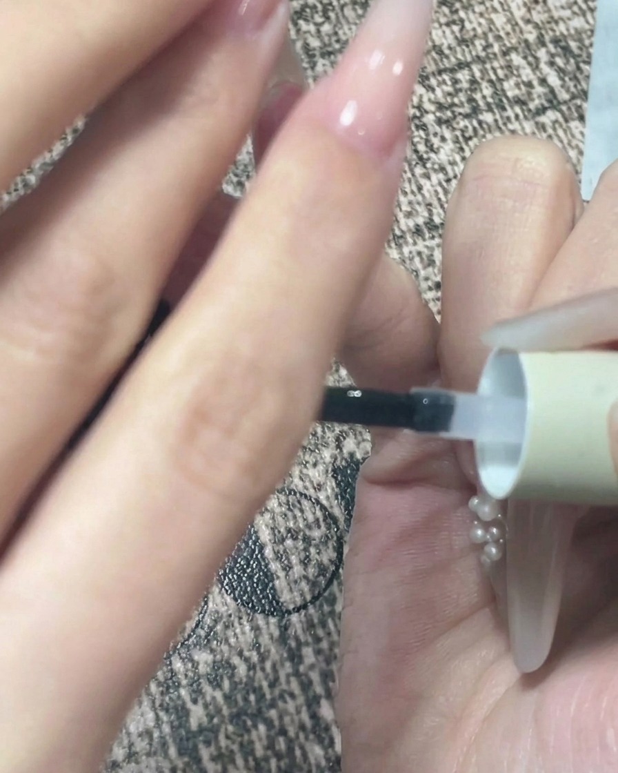 Primo piano di una mano tenuta capovolta dopo lapplicazione del top coat per consentire al gel di autolivellarsi.
