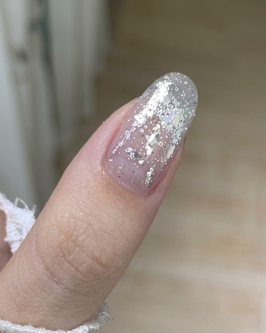 Primo piano di uno strumento in metallo che solleva delicatamente il bordo di uno strato di vecchio smalto gel dallunghia.