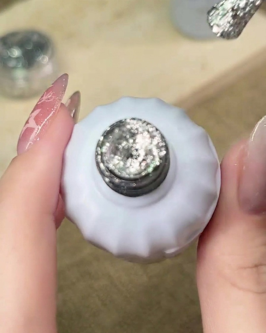 Un pennello che applica gel glitter argento sul bordo libero dellunghia per iniziare la sfumatura.