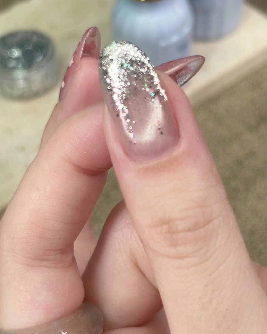 Primo piano di uno strumento che posiziona una piccola stella metallica su ununghia con sfumatura glitter.