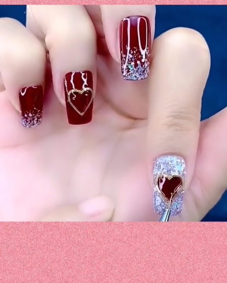 Un pennello per nail art che applica il top coat attorno ai bordi di un charm a cuore metallico.