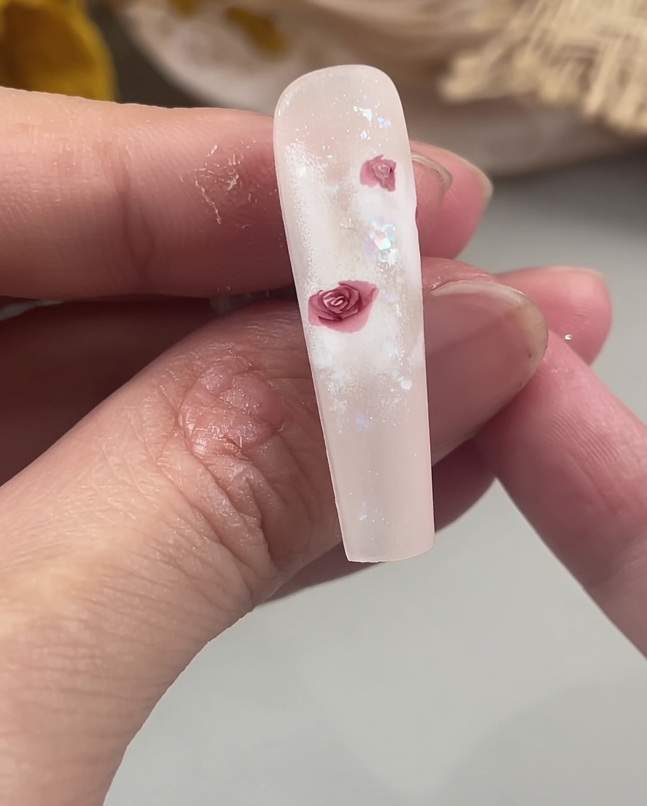 Un pennello di precisione riempie i centri dei petali di una rosa sullunghia per creare una forma floreale solida e definita.