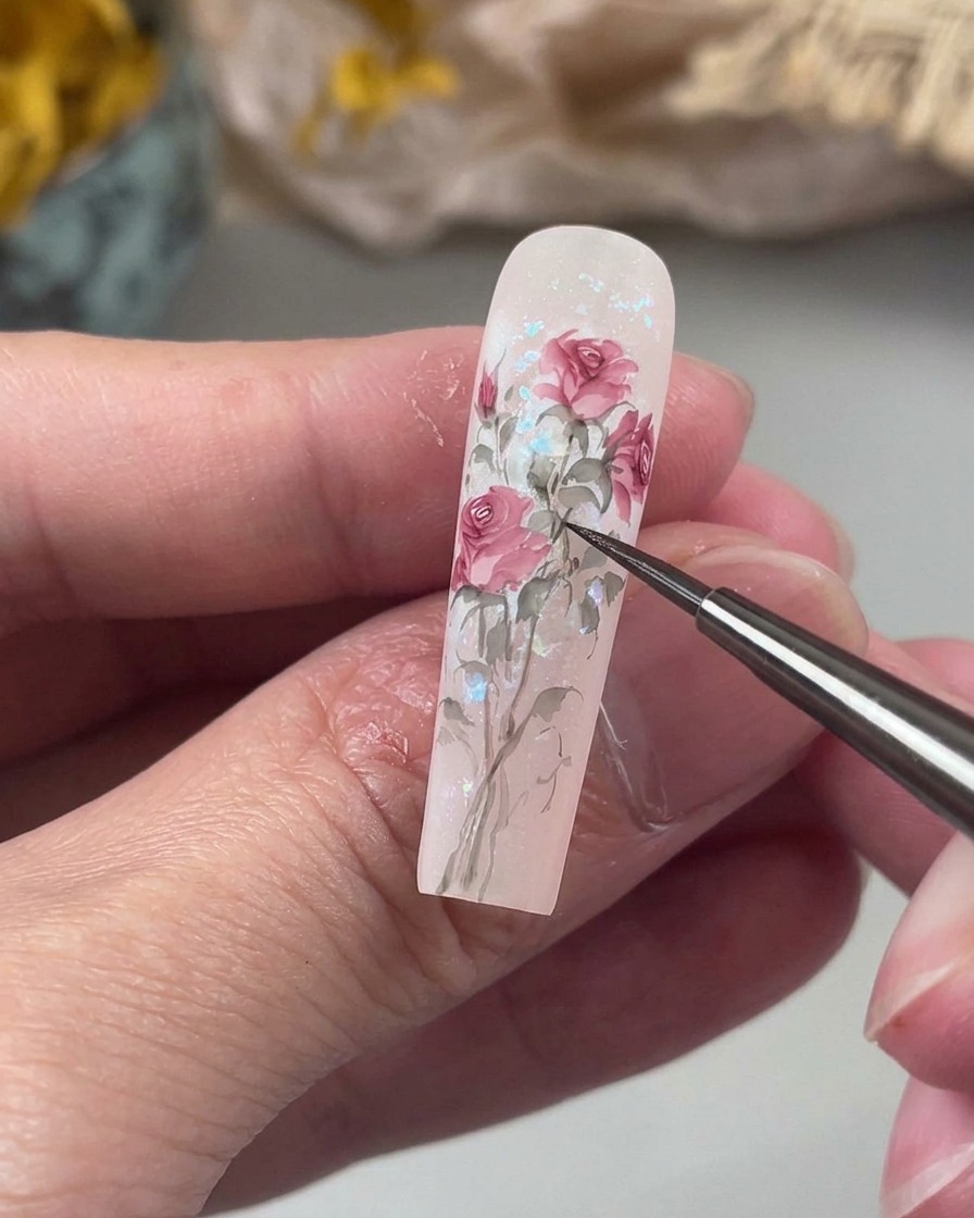 Un pennello di precisione disegna steli delicati e leggermente curvi in una morbida tonalità di verde, collegando gli elementi floreali dipinti sullunghia.