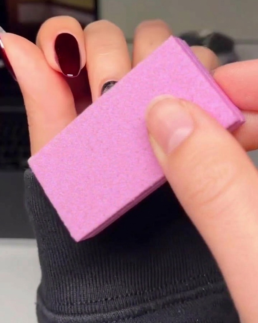 Un pennello liner sottile che contorna con cura un cuore rosso su ununghia con smalto gel nero.