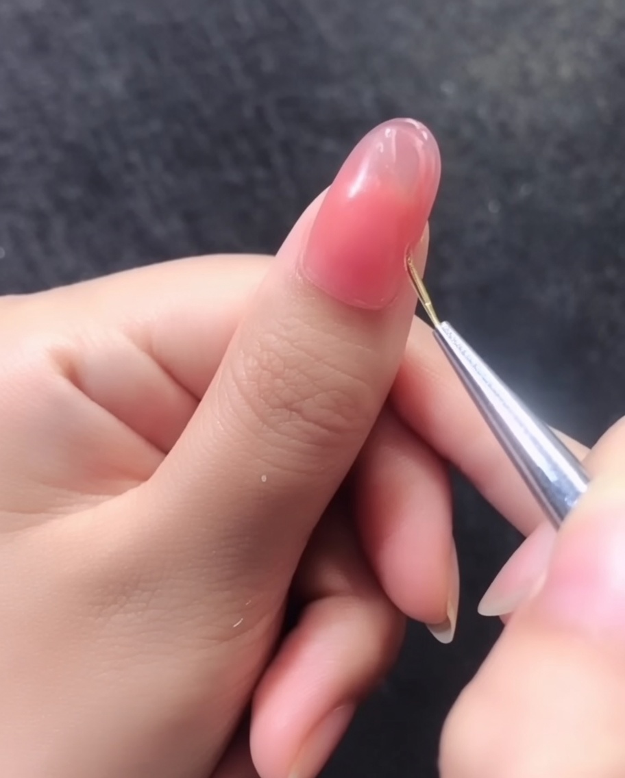 Vista dettagliata di un motivo di linee dorate 3D completato su ununghia in gel rosa.