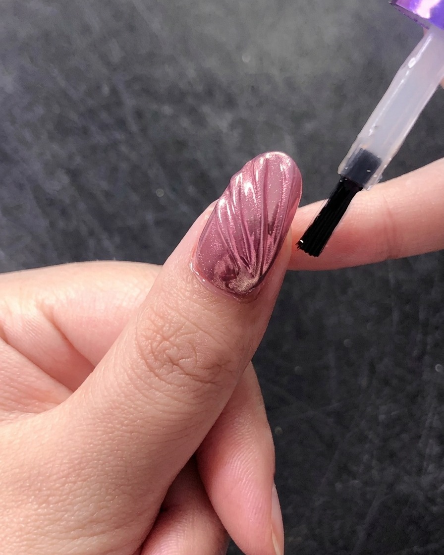 Un pennello che applica un top coat lucido finale su un design a conchiglia cromato.