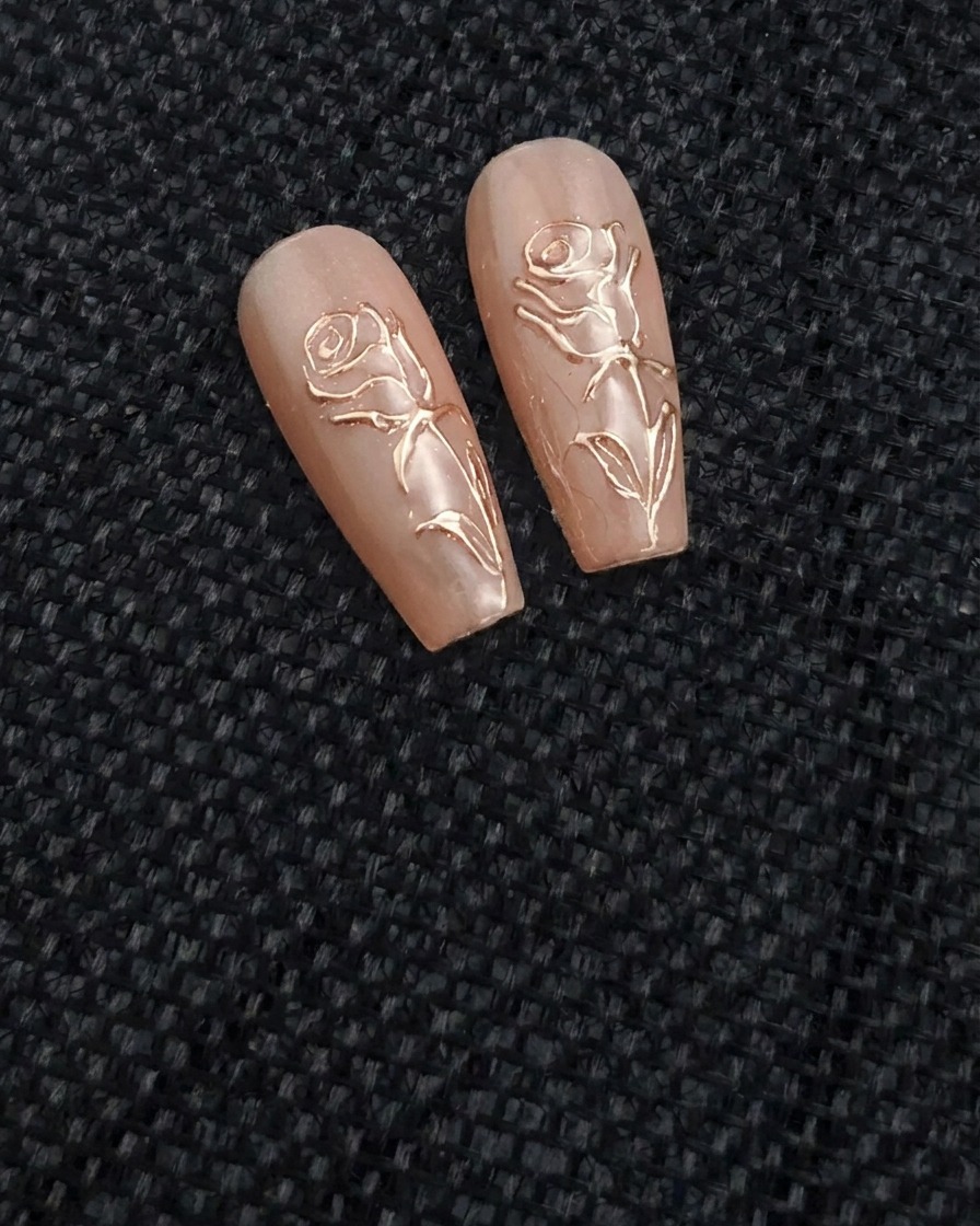 Un pennellino da nail art a punta fine applica una linea di gel trasparente in rilievo a forma di rosa su ununghia nude.