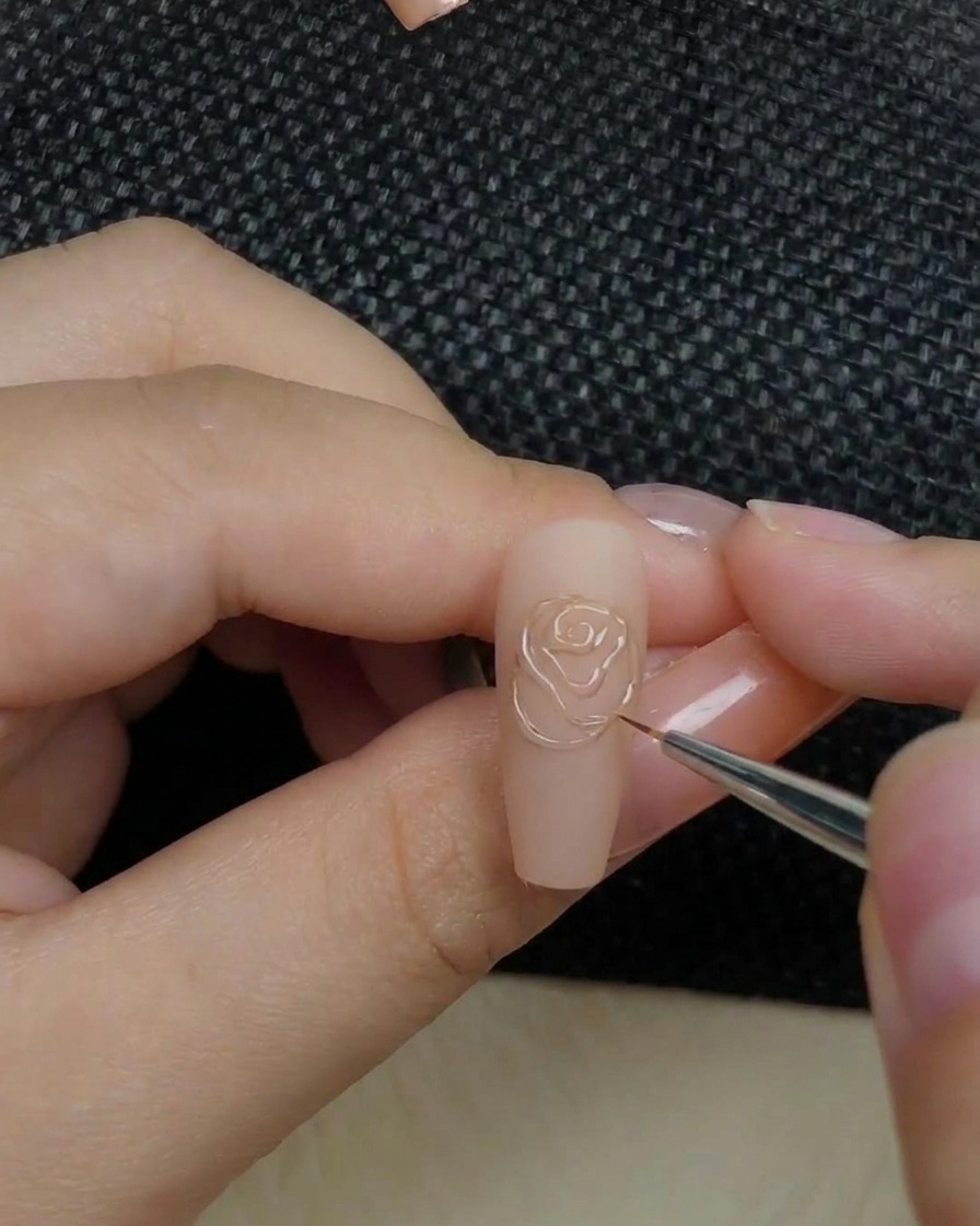 Un primo piano di una mano che inserisce ununghia con un design a forma di rosa in rilievo allinterno di una lampada per unghie.
