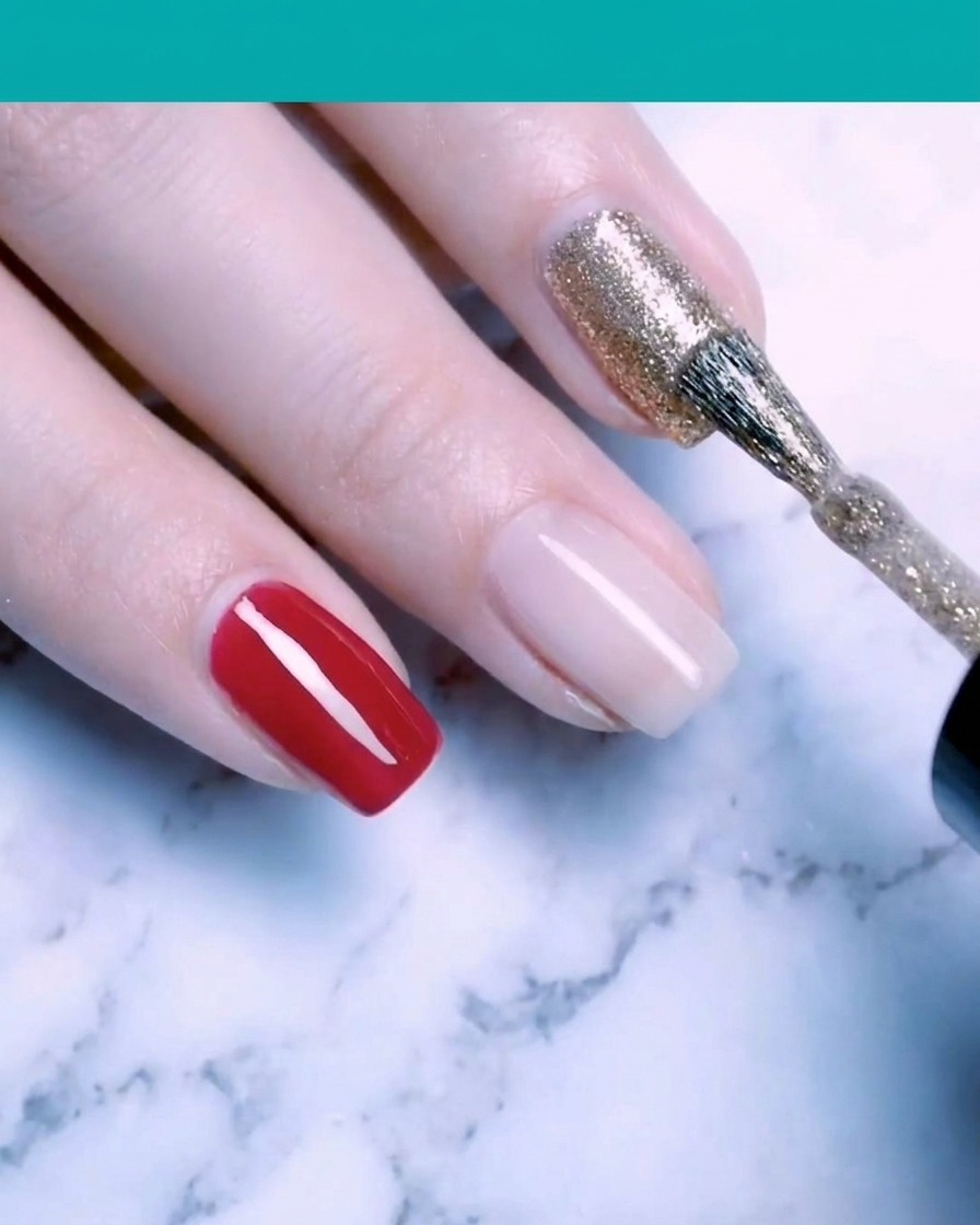 Un pennello per unghie che applica smalto gel glitter oro fine su ununghia.