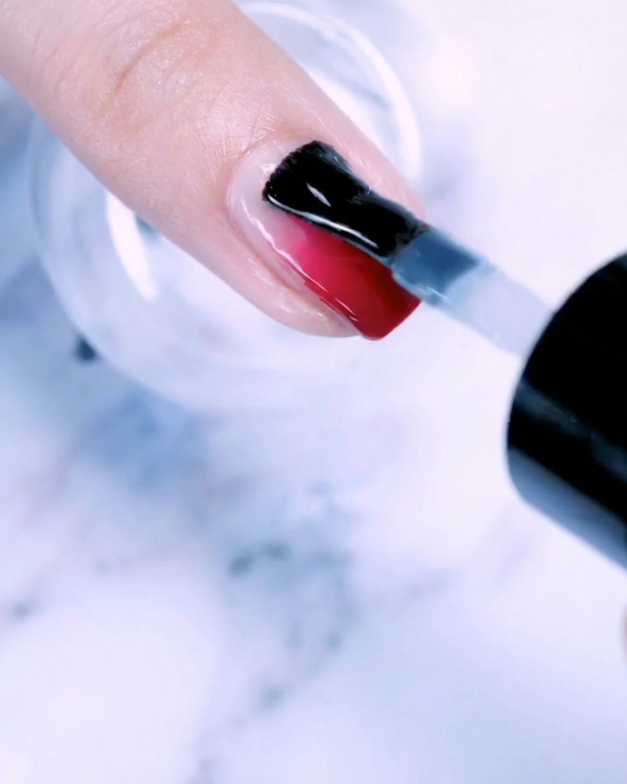 Un pennello che applica uno strato trasparente di gel base su ununghia con gradiente rose gold.