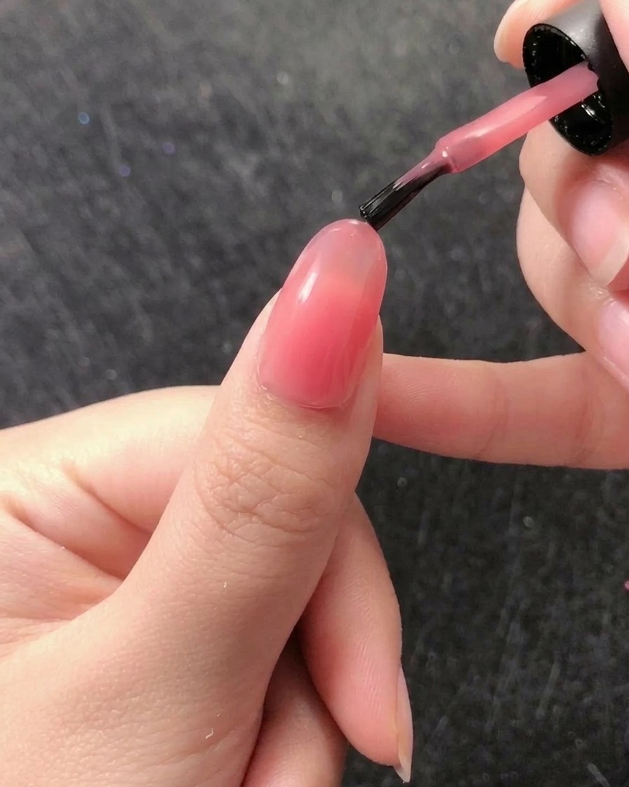 Un pennello liner sottile preleva una piccola perla di builder gel trasparente dal vasetto.