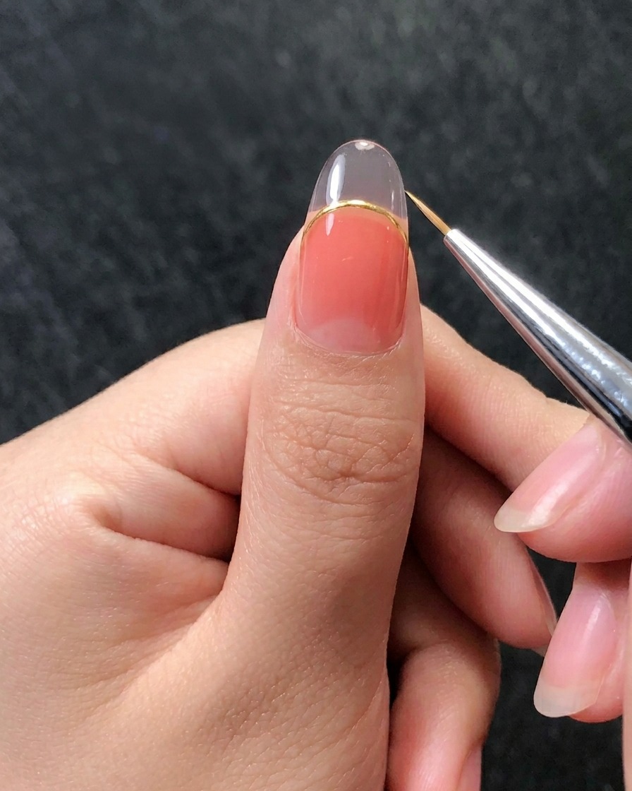 Primo piano di un pennello liner che crea linee verticali in rilievo sullunghia per imitare il motivo di una conchiglia.