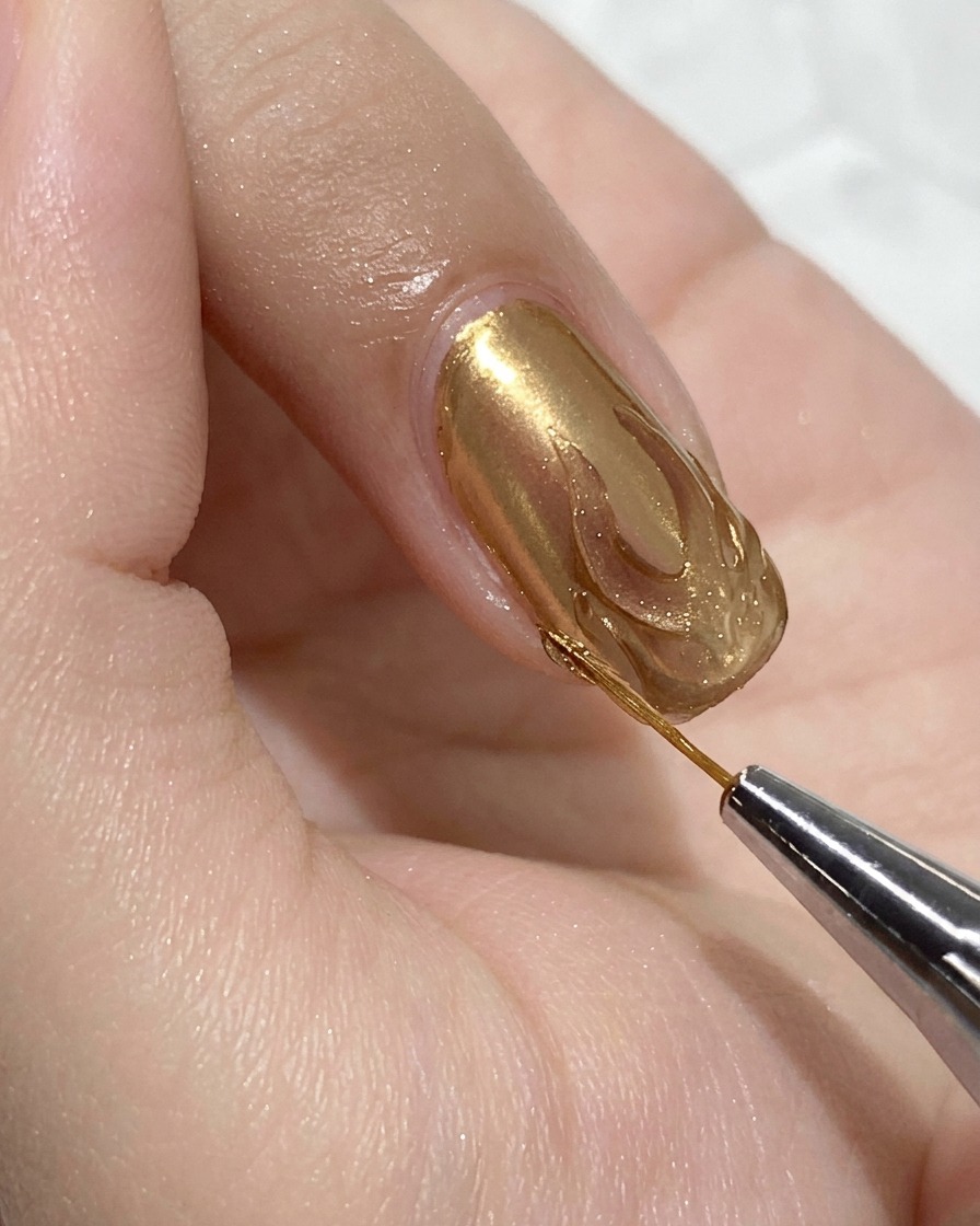 Un pennello di precisione applica gel costruttore trasparente allinterno del contorno della fiamma su ununghia rosa.