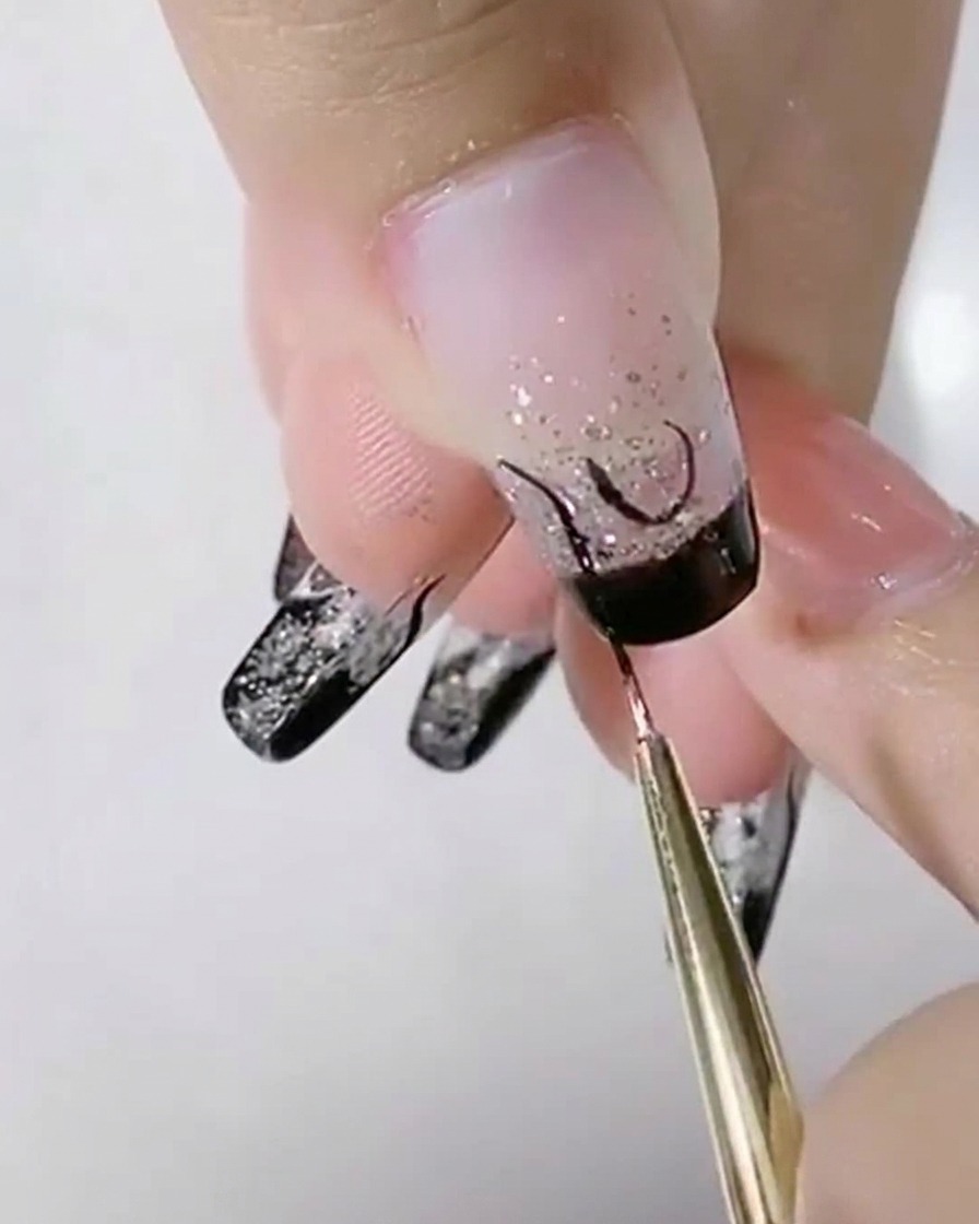 Un pennello liner che aggiunge curve nere a S accanto a una forma a U centrale su ununghia glitter.