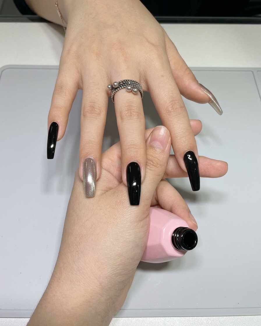 Primo piano di un pennello sottile da nail art caricato con smalto gel nero da una piccola tavolozza.