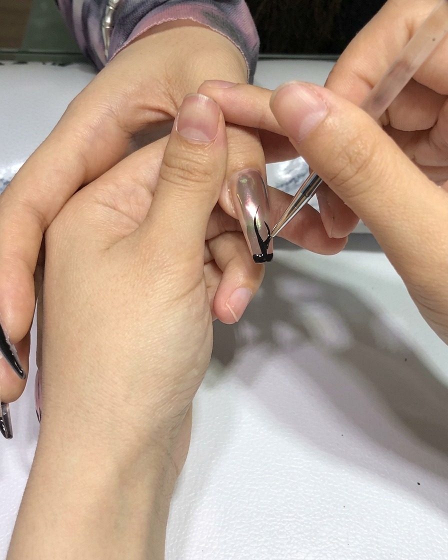 Una mano con la nail art a fiamma nera completata posizionata allinterno di una lampada professionale per unghie.