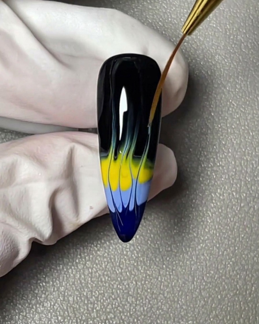 Una striscia orizzontale di smalto gel giallo applicata direttamente sopra la banda blu sulla punta dellunghia.