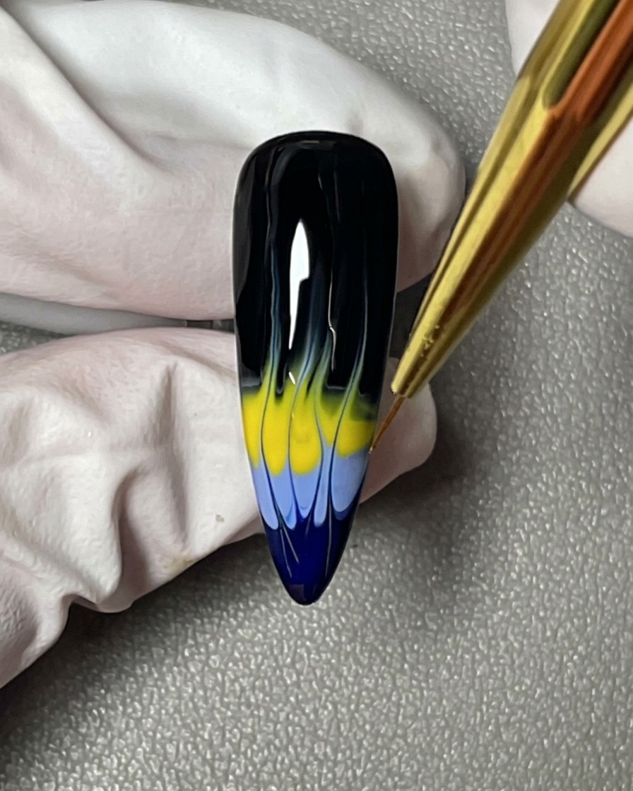 Un primo piano che mostra un pennello a punta sottile che perfeziona le punte affilate del design a fiamma blu e giallo.