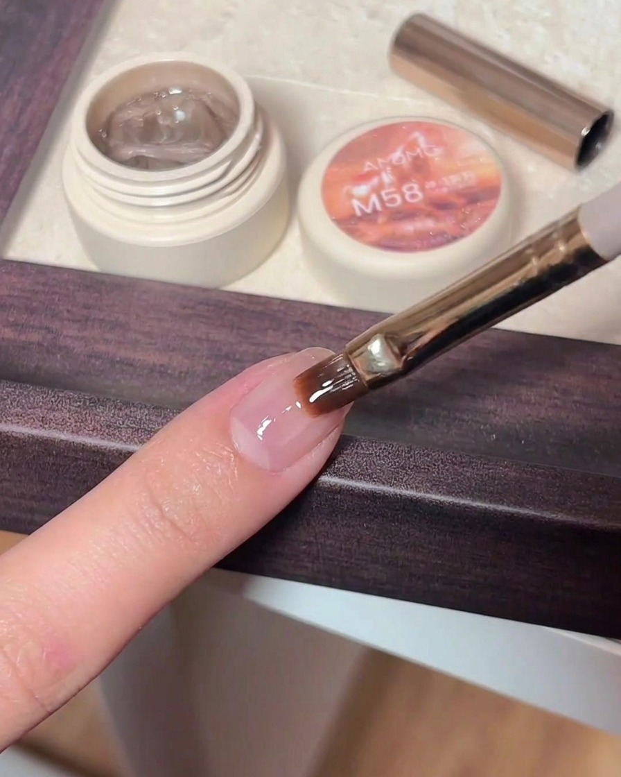 Pinzette che posizionano piccoli glitter a forma di stella su ununghia con top coat ancora umido.