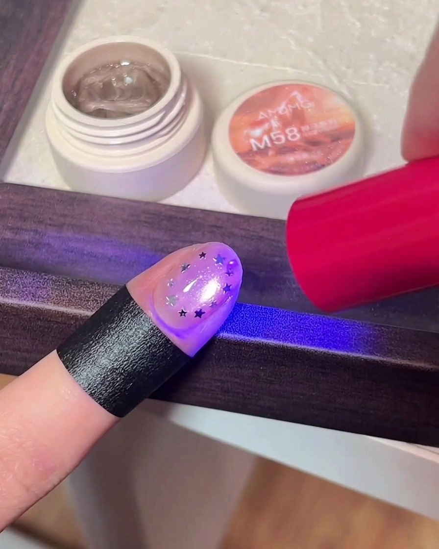 Ununghia con decorazione a stella sotto la lampada UV/LED.