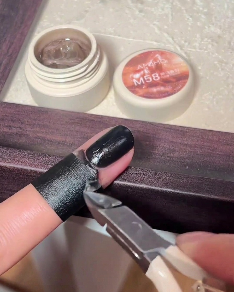 Uso di un pennellino per nail art per applicare gel nero su un ciondolo a croce.
