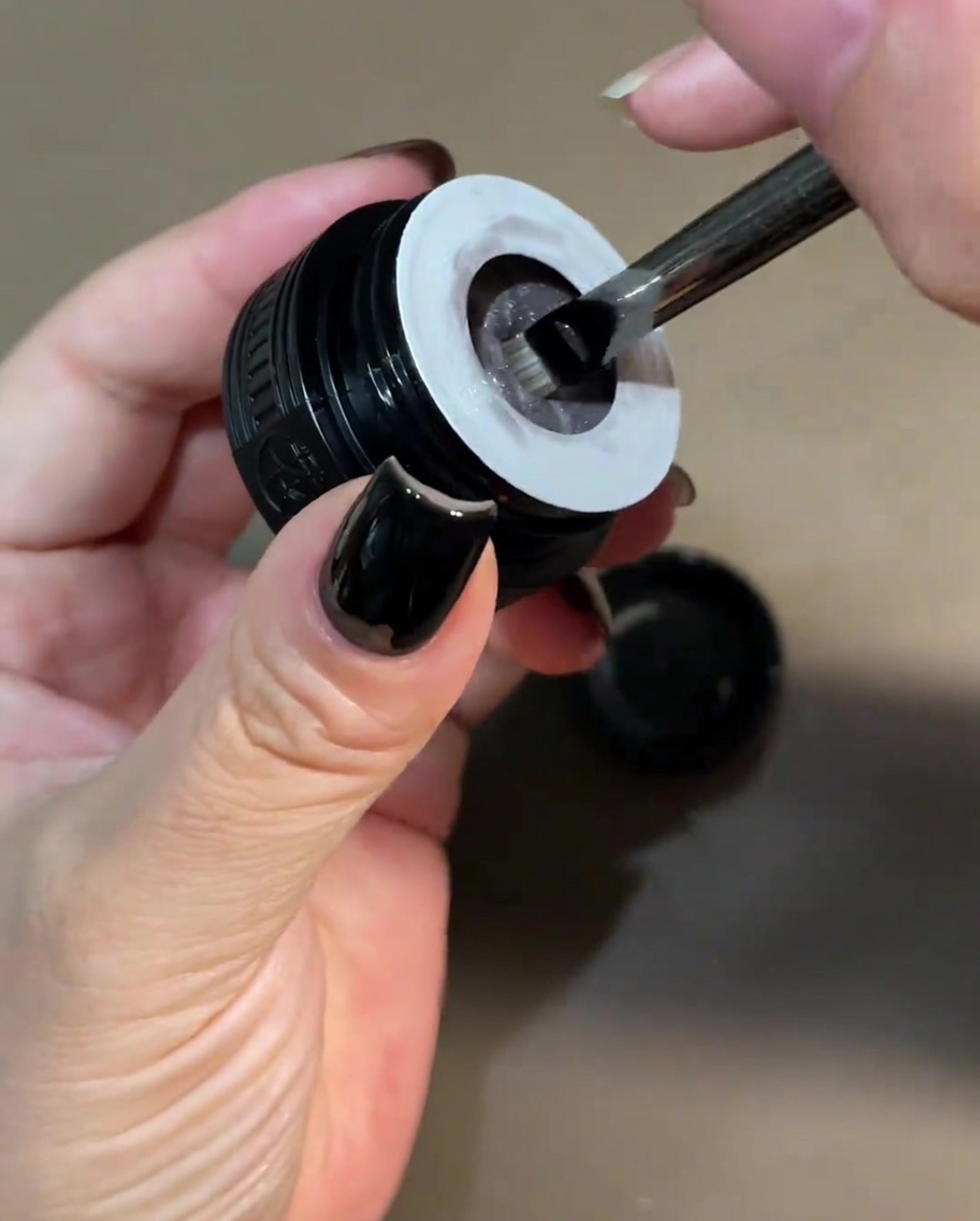 Un piccolo pennello che preleva del gel cat-eye bianco perlato da un vasetto.