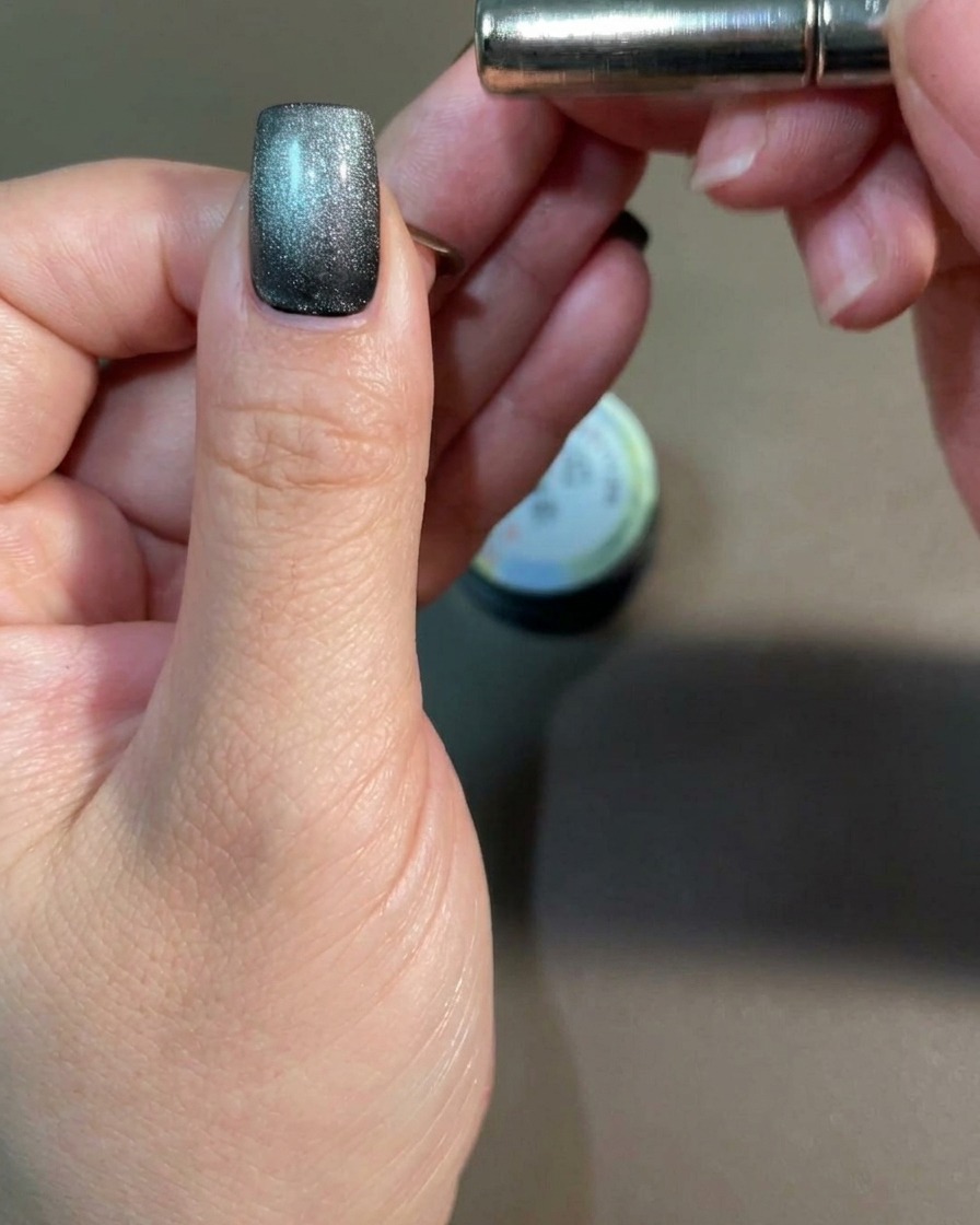 Un magnete a barra tenuto vicino al lato di ununghia per influenzare il pigmento cat-eye.