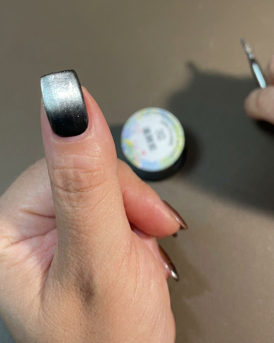Una mano con un design sfumato cat-eye finito che polimerizza allinterno di una lampada per unghie.