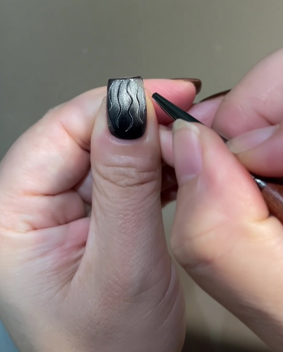 Una vista dettagliata che mostra la base della nail art a fiamma collegata con sottili linee incrociate utilizzando un pennello liner.