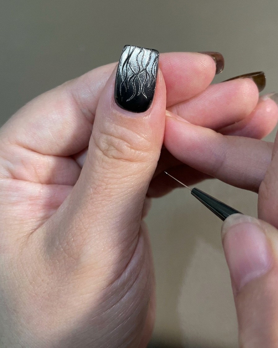 Una mano con nail art a fiamma completata posizionata sotto una lampada UV professionale per la polimerizzazione.
