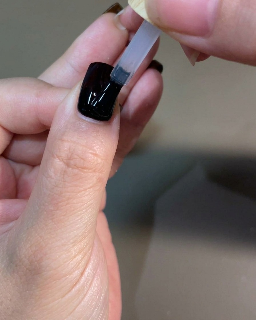 Una mano curata che polimerizza lo strato finale di top coat allinterno di una lampada UV professionale per unghie.