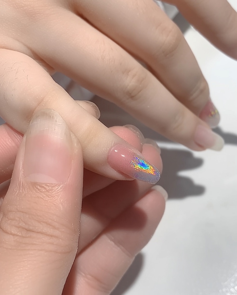 Una mano posizionata allinterno di una lampada UV per unghie per polimerizzare la polvere appena applicata.