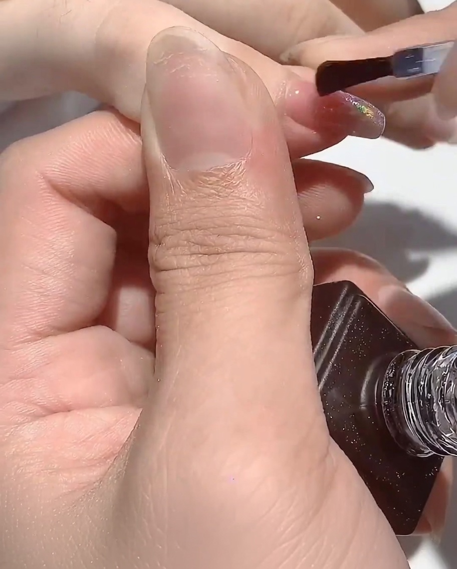 La mano appoggiata sotto la lampada UV, con le unghie che polimerizzano.