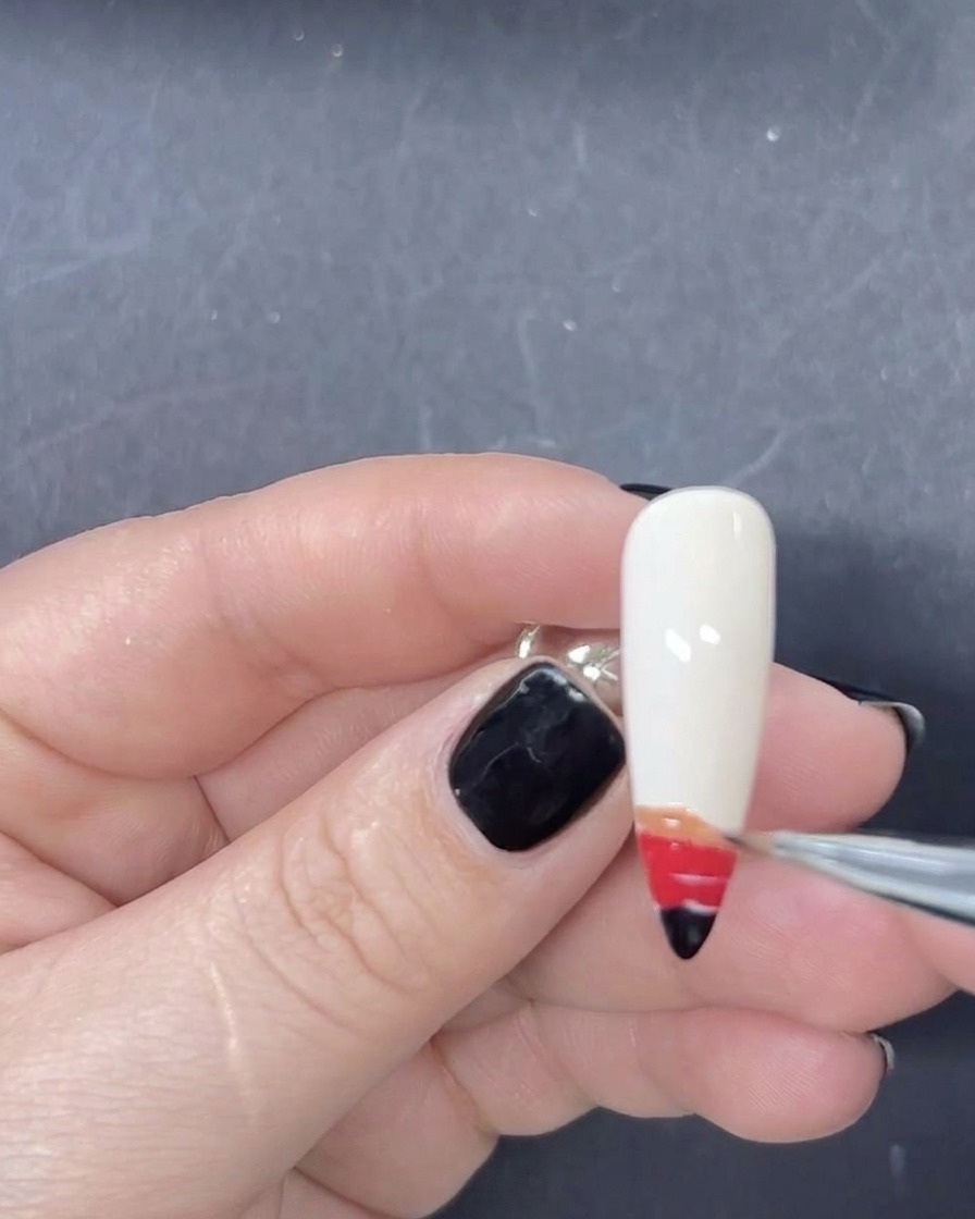 Un pennello liner sottile che aggiunge una striscia arancione di smalto gel alla sequenza sfumata sullunghia.