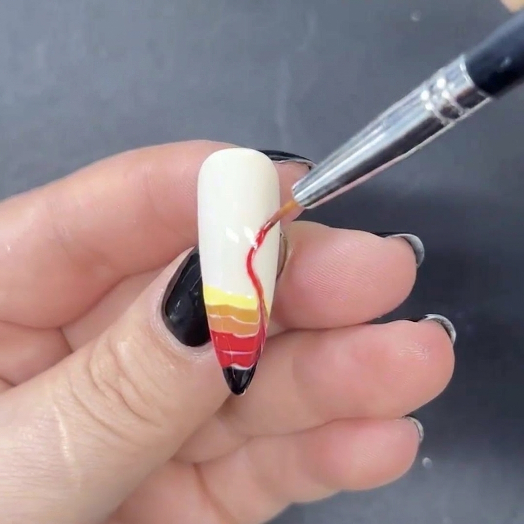 Un pennello liner sottile utilizzato per trascinare le strisce orizzontali di gel colorato verso lalto in disegni di fiamme a forma di S.