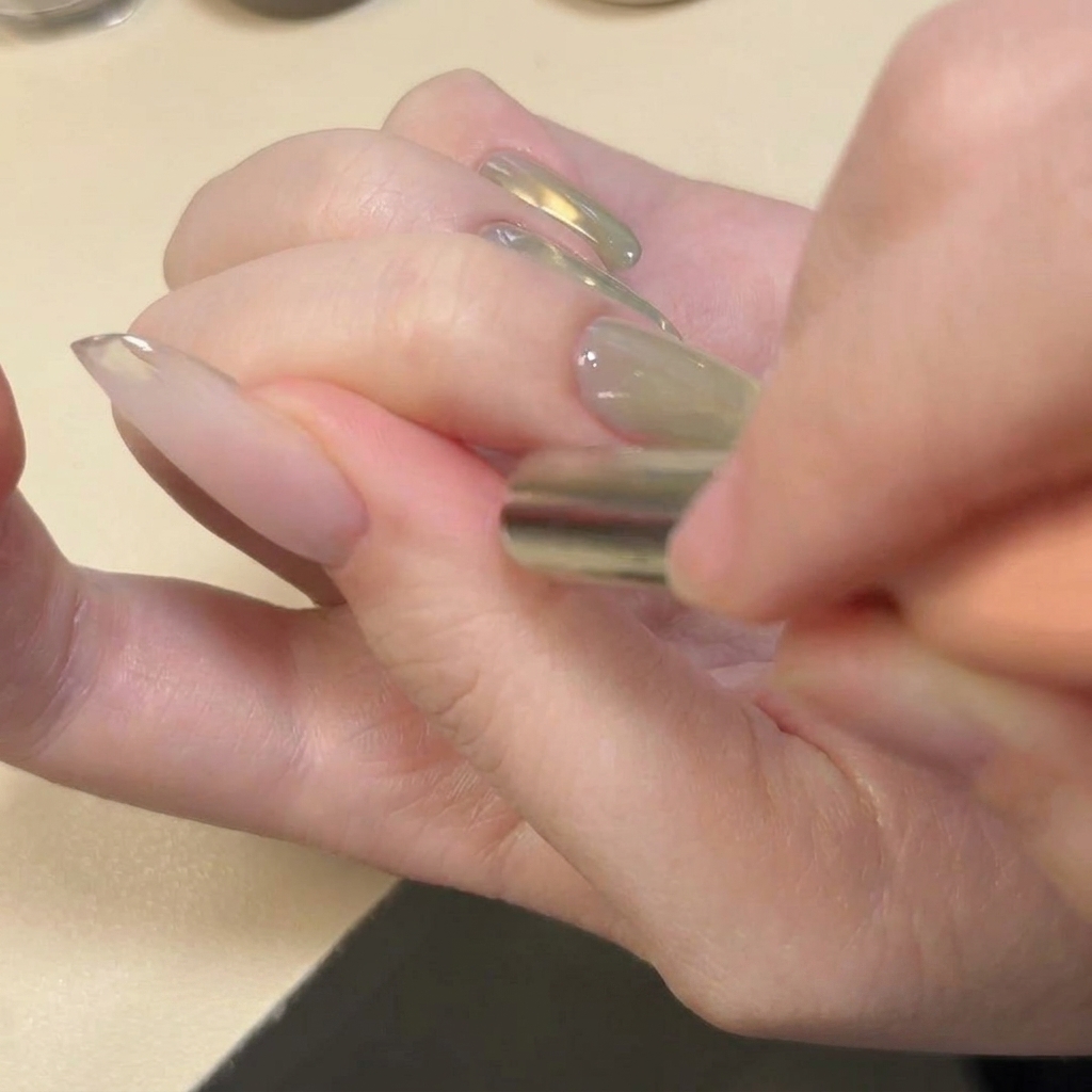 Un magnete posizionato orizzontalmente sulla punta dellunghia per creare un motivo di glitter a forma di U.