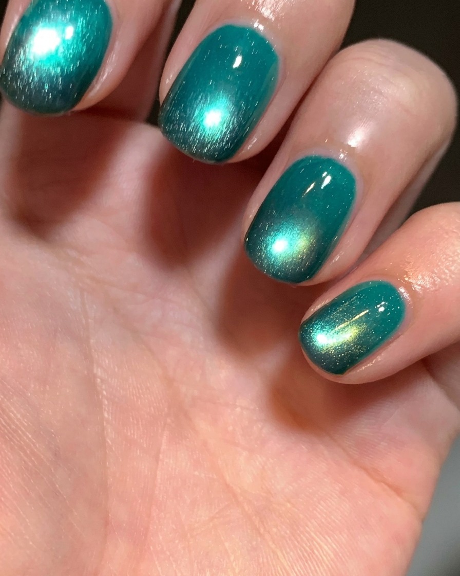 Primo piano di una punta di dito dove viene applicato del gel nero sullunghia naturale usando una piccola spugnetta cosmetica.