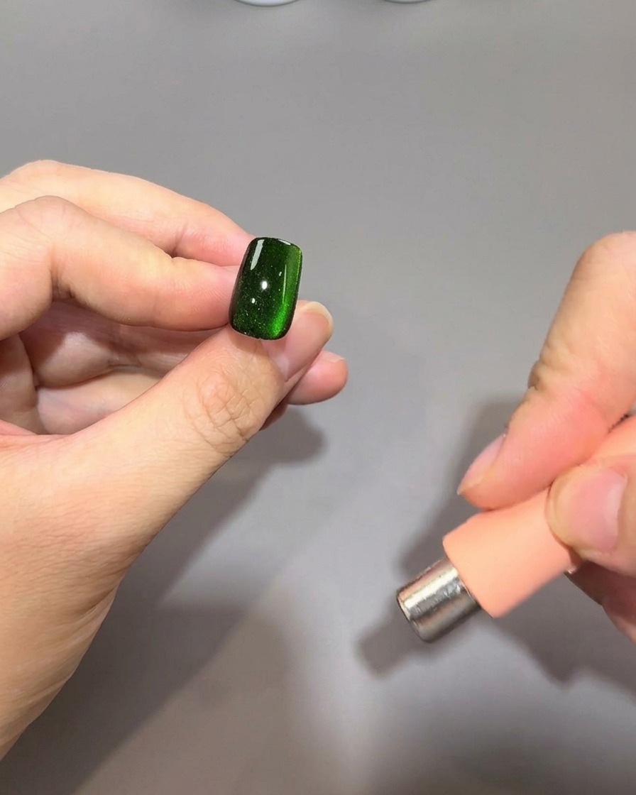 Un magnete cilindrico tenuto parallelamente al bordo destro di ununghia per continuare a modellare il riflesso magnetico.