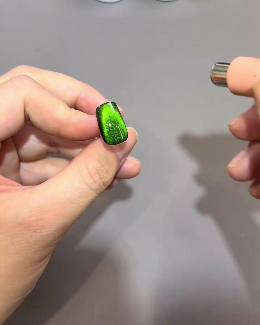 Un magnete esegue un movimento a forma di C sulla punta dellunghia per concentrare le particelle magnetiche in una forma arrotondata simile a una perlina.