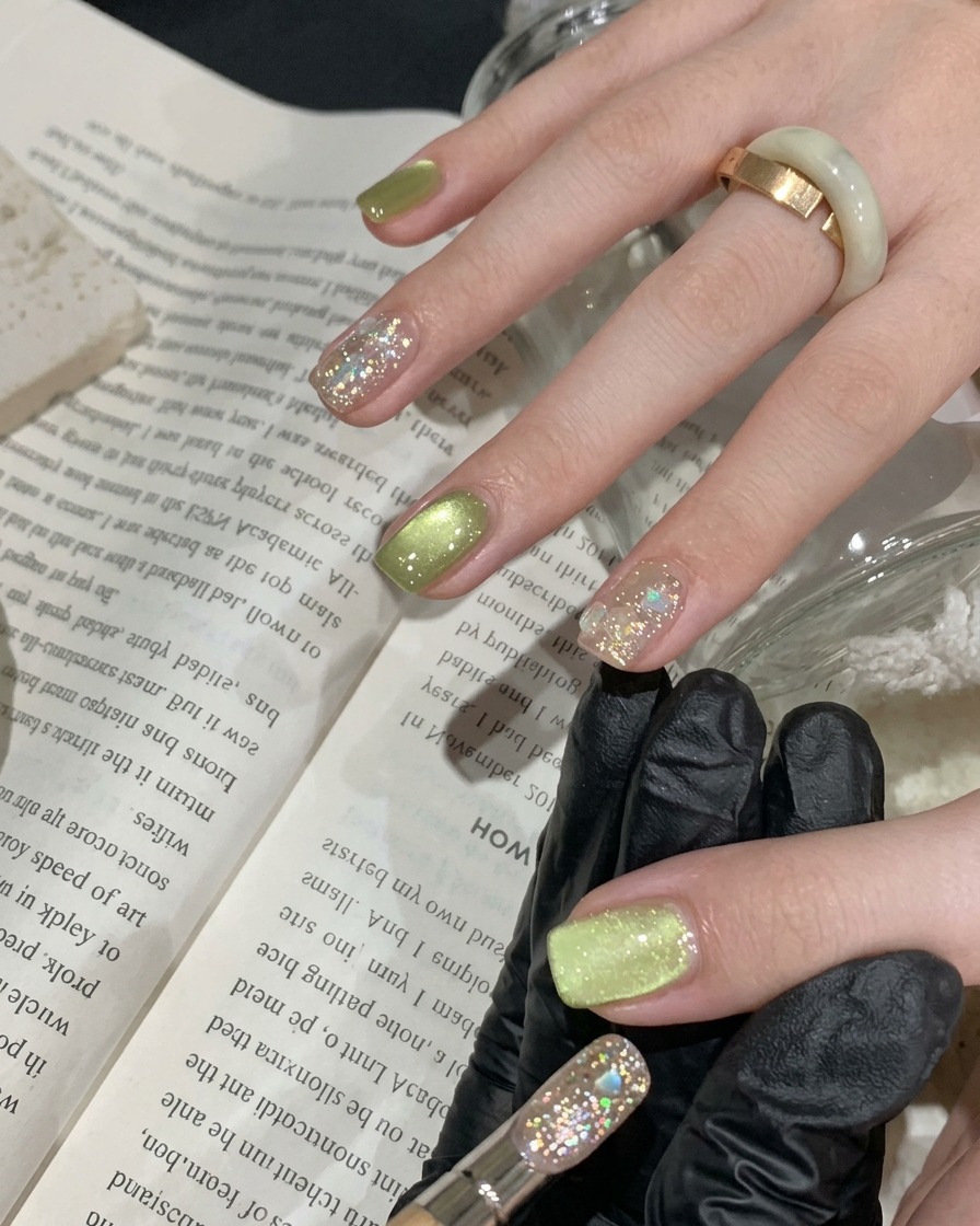 Un pennello applica uno strato sottile di smalto gel cat-eye verde vibrante su ununghia naturale.